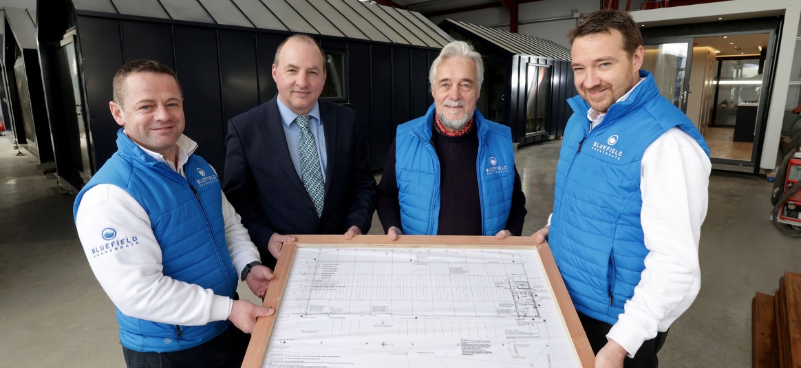 Four Bluefield employees holding plans of a houseboat new build.