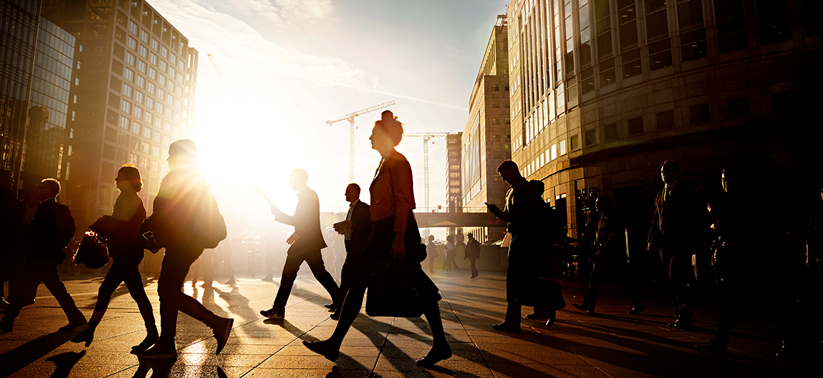 Photo of people walking in early city sunlight